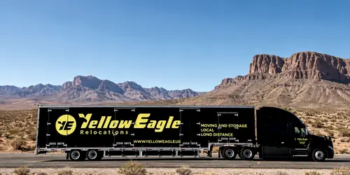 A Yellow Eagle tractor and trailer, side on, before desert hills