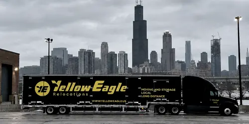 A Yellow Eagle tractor and trailer, side on, before a winter city waterfront