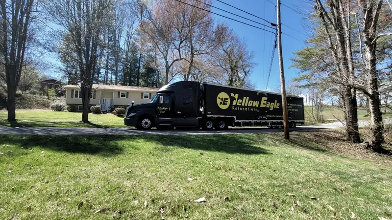 A Yellow Eagle tractor and trailer on a residential street beside a house